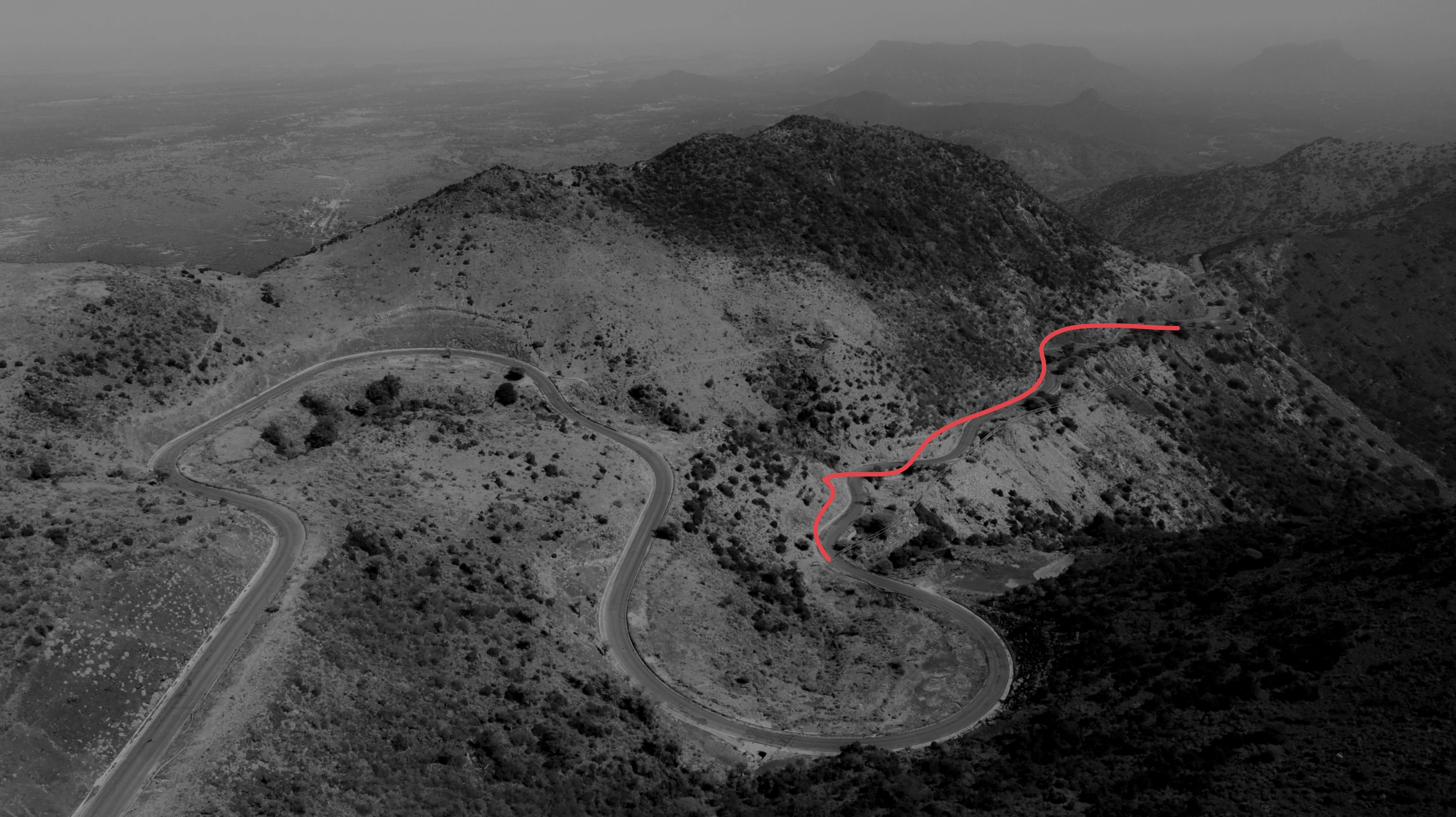 Dark hills with a red road curving through the landscape